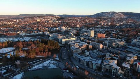 Aerial POI clockwise slow moving footage of city and traffic on e18 highway at Skoyen urban area in Oslo, Norway at sunrise in spring 2019