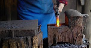 Close up of One senior Asian blacksmith working in the shop, strike a hot red metal with a hammer, making farm tool, traditional craftsman working in workshop slow motion clip