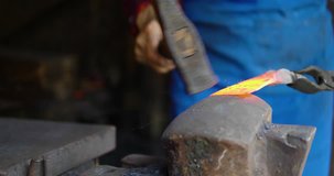 Close up of One senior Asian blacksmith working in the shop, strike a hot red metal with a hammer, making farm tool, traditional craftsman working in workshop 4k clip