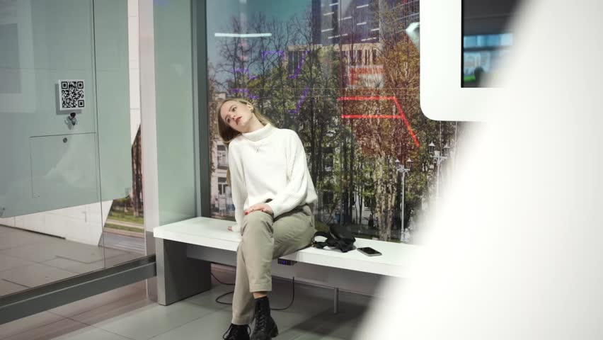 Young woman looking around and waiting for a bus at bus stop.