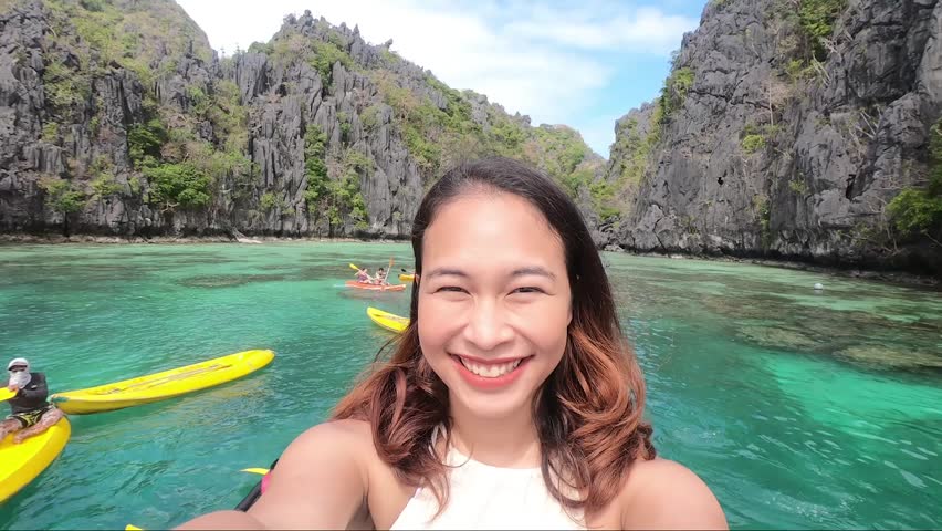 Cheerful enthusiastic Asian tourist girl happily turn around on local boat at Small Lagoon in El Nido, Palawan Island, Philippines. (Selfie shot) Royalty-Free Stock Footage #1026055271