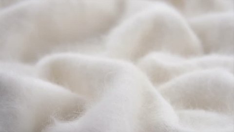 Soft white Wool background. Alpaca wool mohair clothes texture closeup. Natural Cashmere Soft and fluffy merino wool macro shot. Woolen fabric. Knitted hairy detail texture surface. 4K UHD slow motion