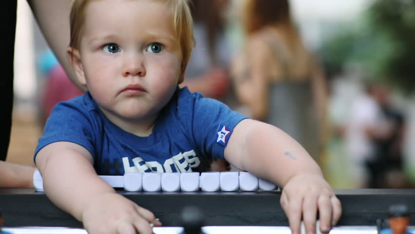 Cute portrait of small adorable kid playing board soccer with his mother indoors. Exciting childhood. Close-up.
