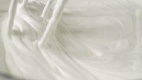 Whipping white cream with a mixer in slow motion