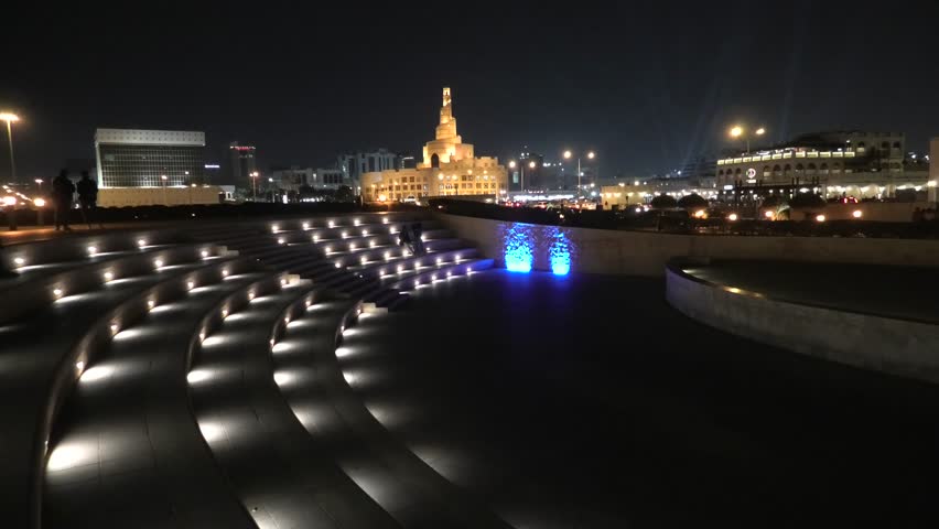 Stairs of small amphitheater at Souq Waqif Garden near Doha Corniche with Doha mosque at night. Doha city center in Qatar, Middle East, Arabian Peninsula in Persian Gulf.