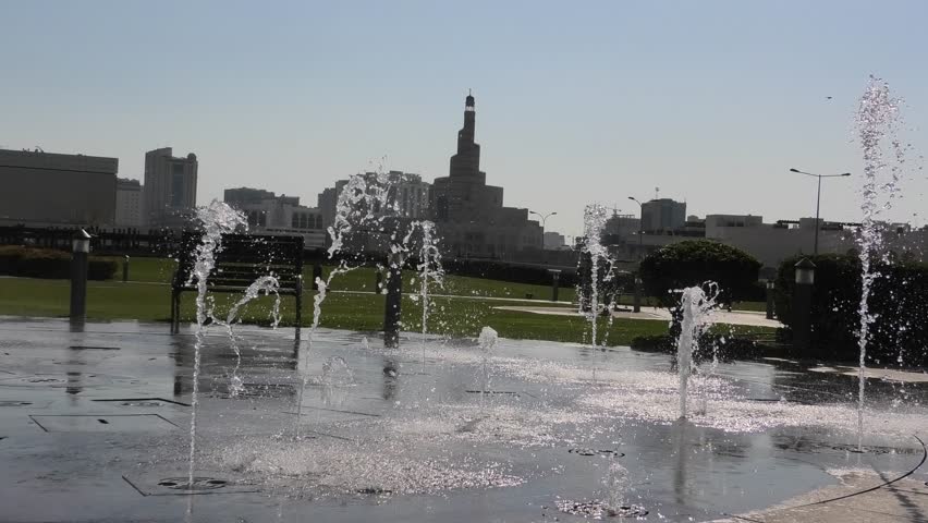 Colorful water fountain at Souq Waqif Park at Doha Corniche with Fanar Islamic Cultural Center and Minaret on background. Doha center in Qatar, Middle East, Arabian Peninsula in Persian Gulf.