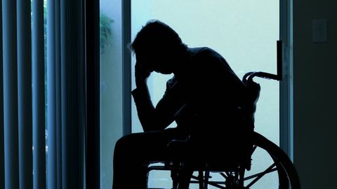 Silhouette of depressed sad man sitting in wheelchair 