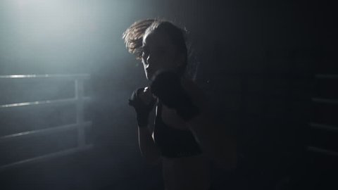 Female boxer fist close up - boxer strikes into the side of the camcorder. Spectator video boxing. The woman is striking the opponent. Slow motion