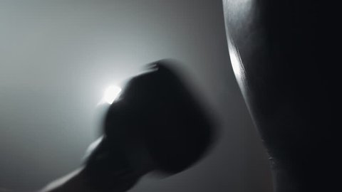 Woman's hand in boxing gloves punching a bag in a boxing club. Close up, slow motion