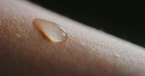 Slow motion macro of fresh cleansing water drop falling on an young smooth healthy human skin. Shot in 8K