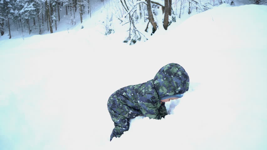 Happy smiling baby boy digging in snowdrift 