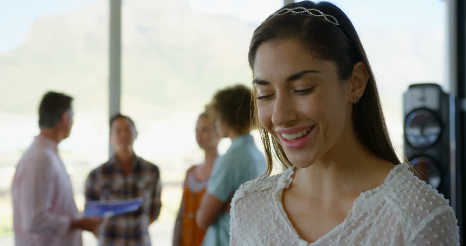Front view close up of happy young Caucasian woman business executive standing in modern office. She is looking at camera