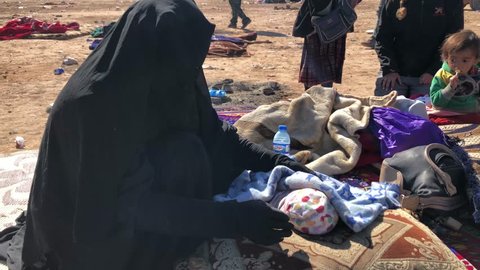 Syria - March 19, 2019: Woman fleeing ISIS comforting her baby