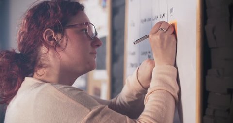 Creative woman is sticking notes on whiteboard