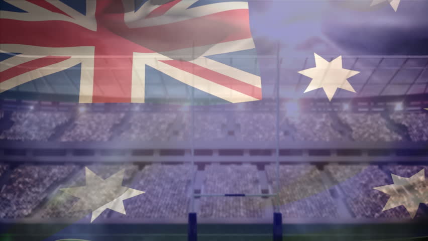 Digital composite of African American rugby player throwing the football away while being tackled down by Caucasian rugby player and Australian flag waving on the foreground in stadium