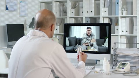 Sequence of videos with male medical physician sitting at commuter and explaining how to take medicines to sick male patient by internet connection