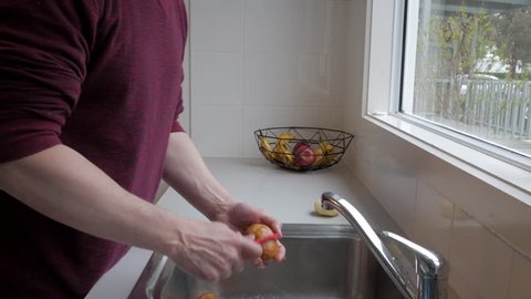 Man peeling potatoes at a kitchen sink.