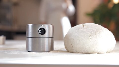 A young girl in the kitchen prepared the dough for baking. Dough on the table, timer for the test