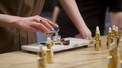 Close up of woman pouring perfume in bottle. Perfume creating workshop