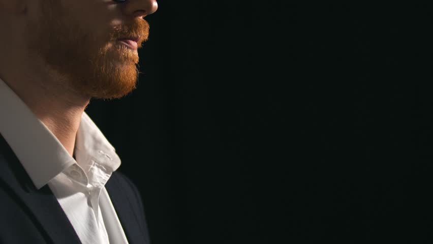 Close up of man smelling and testing brandy isolated on black background