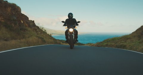 Motorcyclist riding fast on country road with ocean in the background, motorcycle adventure lifestyle
