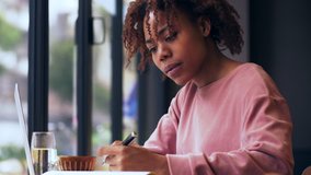 Close up side view of one pretty African college student study writing indoor, Beautiful Black young woman studying education 4k clip. young female freelancer working in the cafe