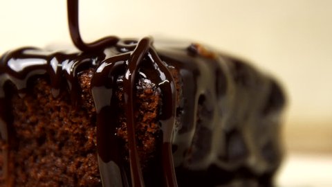 Chocolate icing on cake. Topping chocolate dessert. Chocolate glaze pouring on homemade dessert. Close up of biscuit cake decoration in 4K resolution
