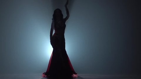 Girl dancing in dress on black smoke background. Sihouette. Slow motion