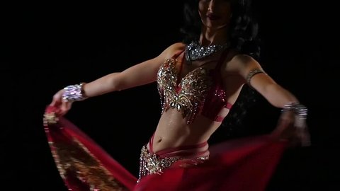 Arab dancer performs belly dance on stage. Black background. Slow motion