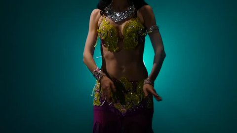 Woman performs a belly dance in oriental costume. Smoke background. Slow motion. Close up