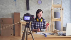 young woman DIY blogger recording video in garage workshop