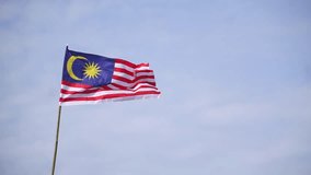 Footage of Malaysia's national flag waving against beautiful cloudy blue sky.