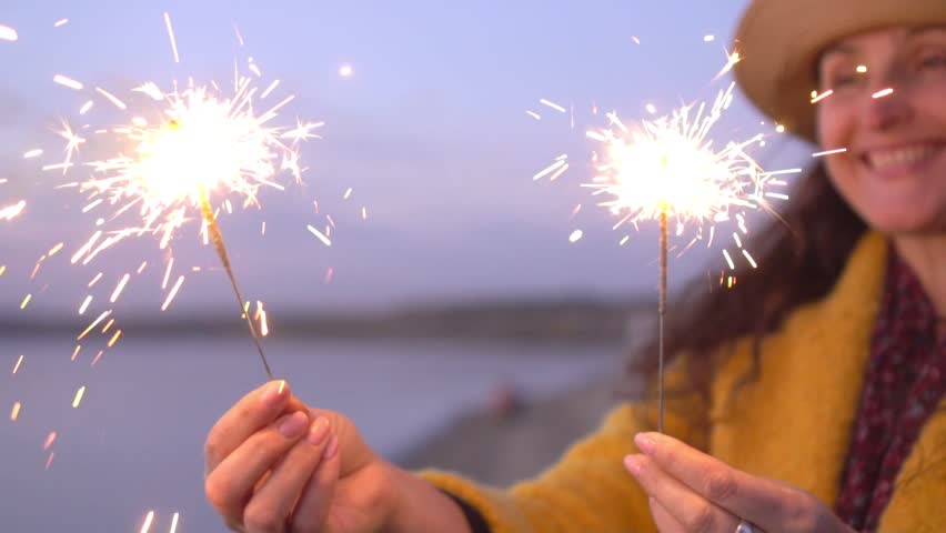 Close up portrait of pretty smilling woman with sparklers in hands close up. Sparks scatters in different directions. | Shutterstock HD Video #1026171353