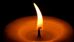 A candle with a large wick burns and stands still on the window sill on a black background at night, footage 4k