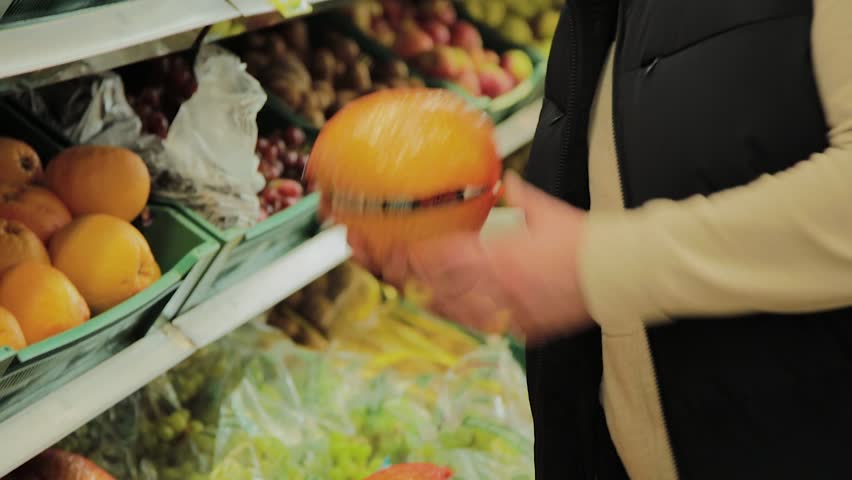 Fat man in the supermarket chooses fruit for himself.