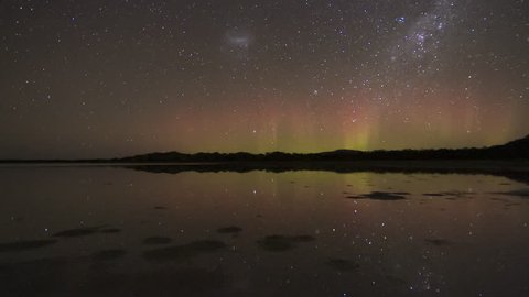 Nature's Fireworks, a display of the Aurora Australis or Southern Lights with beams exploding into the night sky, all reflected in still water in the foreground. Tasmania.