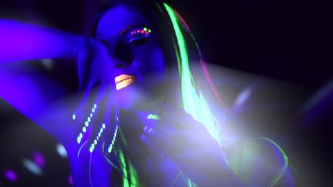 Fashion model woman in neon light, beautiful model girl with fluorescent make-up, Art design of female disco dancer dancing in UV light, colorful make up. Night club, Party. 4K UHD video slow motion