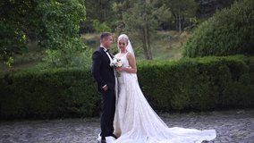 Beautiful wedding couple walking in the park. Bride with long white dress and stylish groom