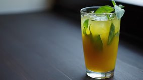 Footage of basil leaves and mint in refreshing cold drink with alcohol. Delicious coctail with gin and juice for hot summer day. Close up on restaurant or bar alcohol menu item