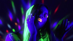 Fashion model woman in neon light, beautiful model girl with fluorescent make-up, Art design of female disco dancer dancing in UV light, colorful make up. Night club, Party. 4K UHD video slow motion