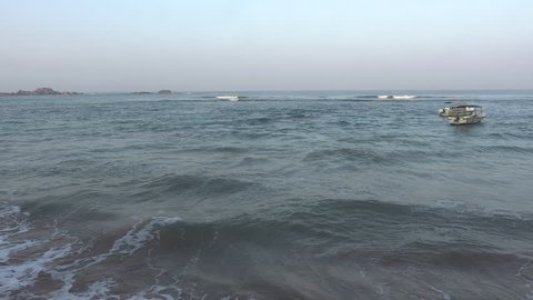 Gentle waves and sea fom break softly over the coarse sand of a popular public beach in Hikkaduwa. Sri Lanka