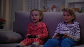 Two children playing game with joysticks caught parents at night, entertainment