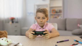 Little girl disturbing brother playing console game, children fighting joystick