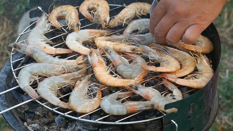 Woman hands turns the shrimp on grill. Grilling shrimps on barbecue. Grilled seafood on bbq