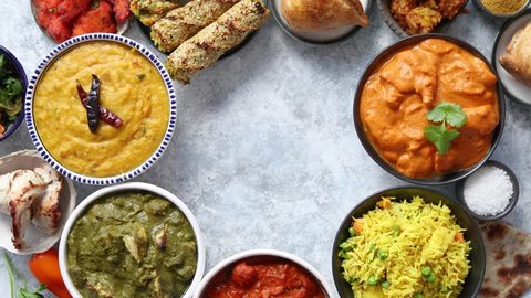 Assorted indian food on stone background. Dishes of indian cuisine. Tikka masala, butter chicken, Nilgiri, seekh kebab, rice, Onion Bhajia, paneer, samosa, naan, Daal Tarka, spices With copy space