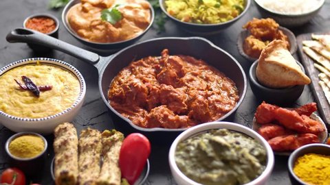 Various Indian dishes on a table. Spicy chicken Tikka Masala in iron pan. Served with rice, naan and spices. Set of different kind Indian food.