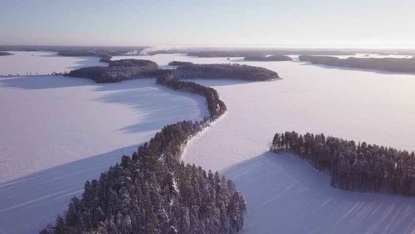 Narrow Punkaharju ridge road and frozen lake Saimaa. Aerial view of Finnish national ladscape in winter.