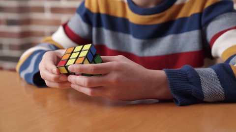 Moscow, Russia – March 24, 2019: A boy assembling the Rubik's cube. Rubik's Cube is a 3D combination puzzle invented in 1974 by Hungarian sculptor and professor of architecture Erno Rubik