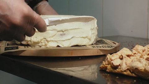 The concept of cooking. A professional pastry chef prepares a delicious lavender cake, applies cream on top and levels it with a spatula, close-up