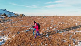 Happy couple traveling together, hiking in the mountains in spring or autumn. Aerial video of man and woman trekking together walking mountain valley. Family travel vacation outdoor.